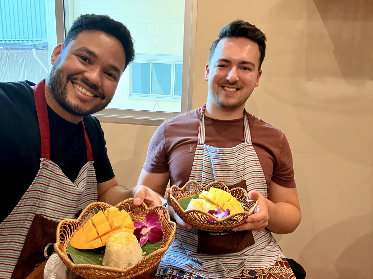 Klaudio and Derick at a cooking class holding their finished dishes