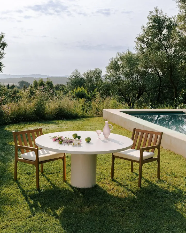A table set for lunch in a sunlit garden beside the pool